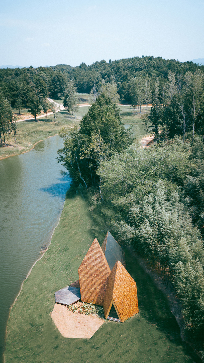 wooden shingles overlay cluster of monolithic cabins on chinese waterfront