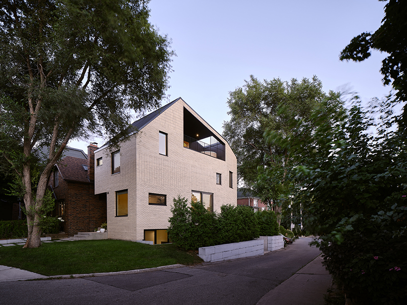 brick residence's sloping roof shields recessed outdoor balcony in toronto