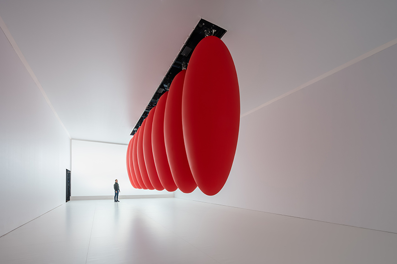 eight suspended red ovoids by SpY dance in pendular sequences