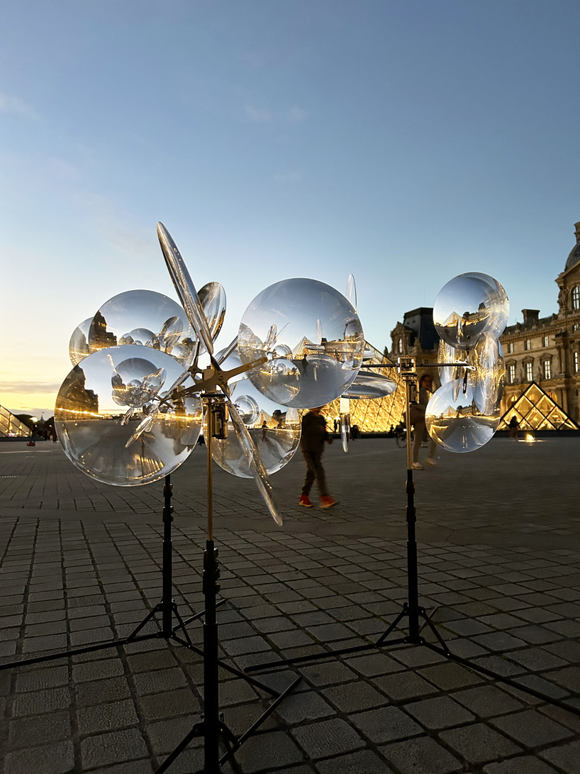 kinetic cloud's floating lenses by vincent leroy deform louvre's facade