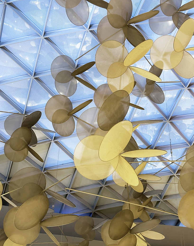 vincent leroy's kinetic installation of metallic mesh flowers floats above hainan island in china