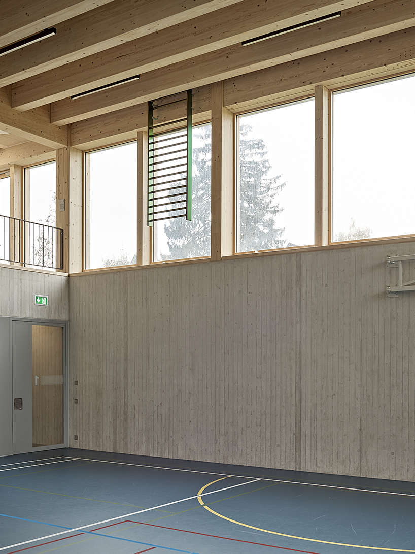 vertical timber construction shapes twin stacked sports halls in switzerland by kit