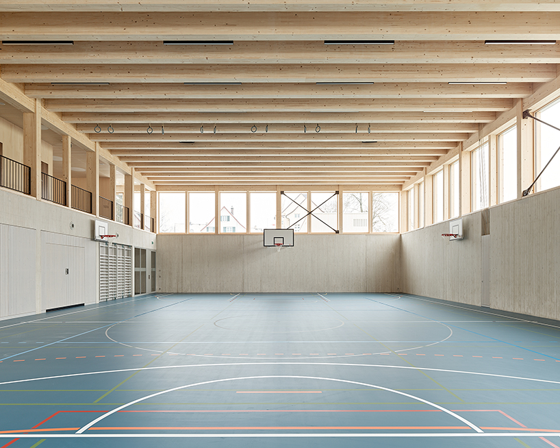 vertical timber construction shapes twin stacked sports halls in switzerland by kit