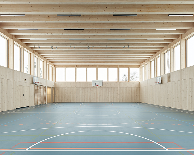 vertical timber construction shapes twin stacked sports halls in switzerland by kit
