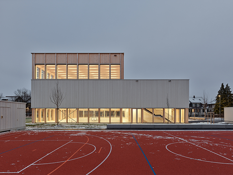 vertical timber construction shapes twin stacked sports halls in switzerland by kit