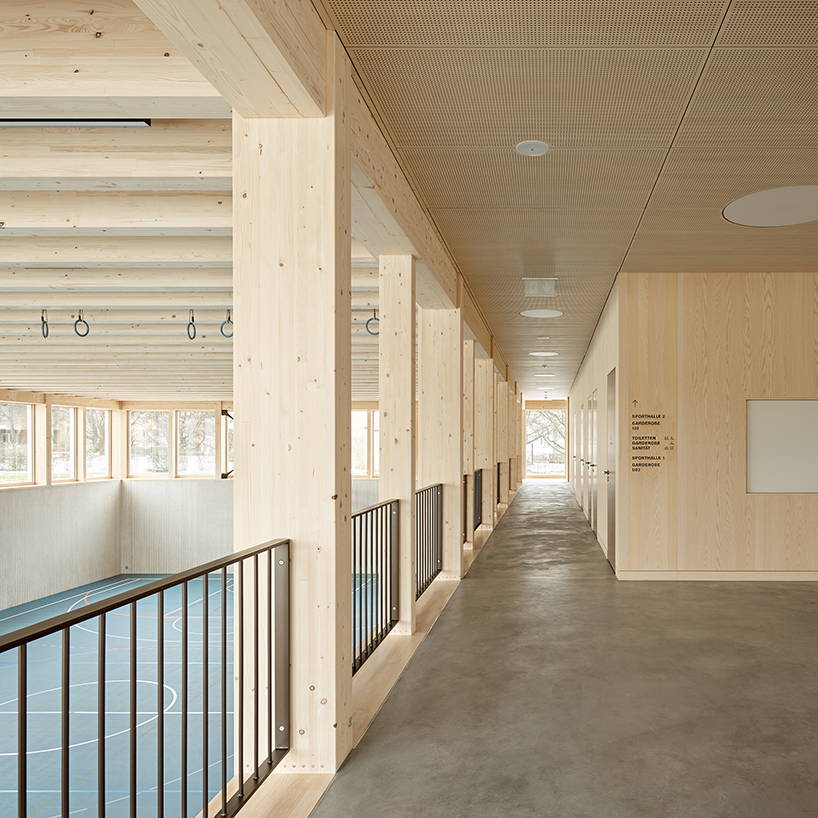 vertical timber construction shapes twin stacked sports halls in switzerland by kit