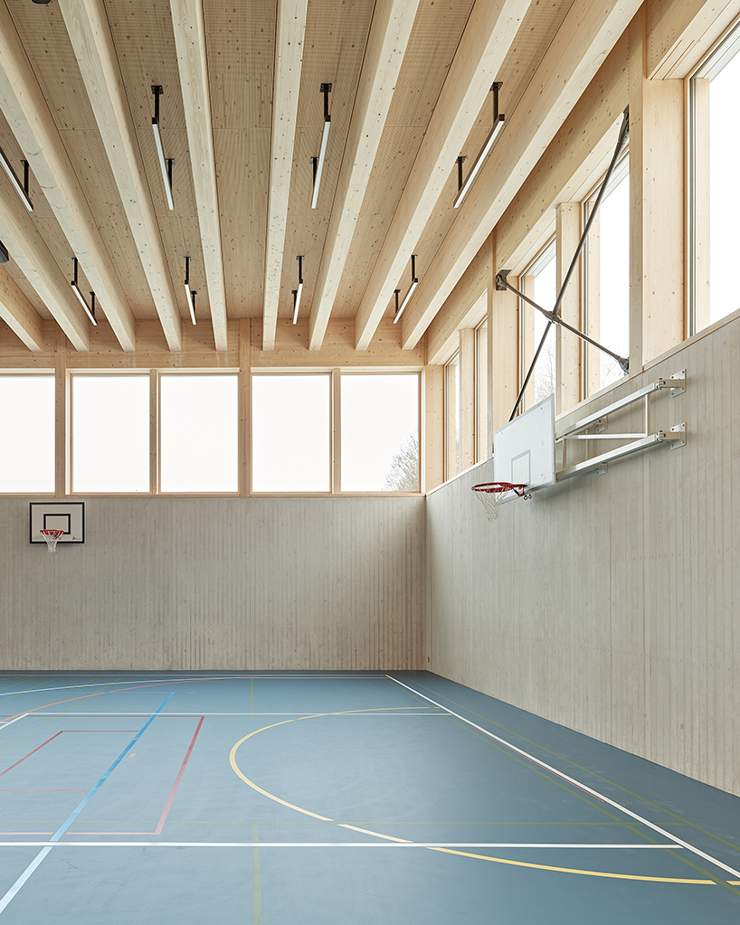 vertical timber construction shapes twin stacked sports halls in switzerland by kit