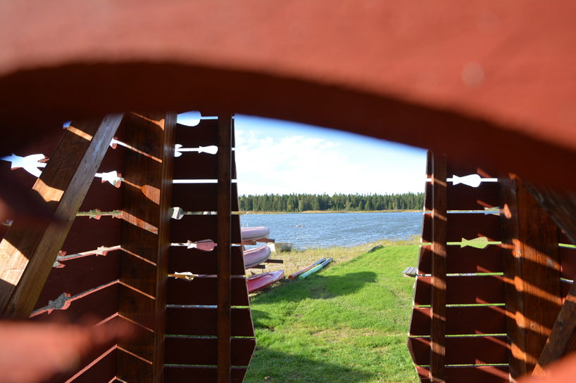 red timber pyramid beacon by ulf mejergren glows through fish cutouts on baltic sea island