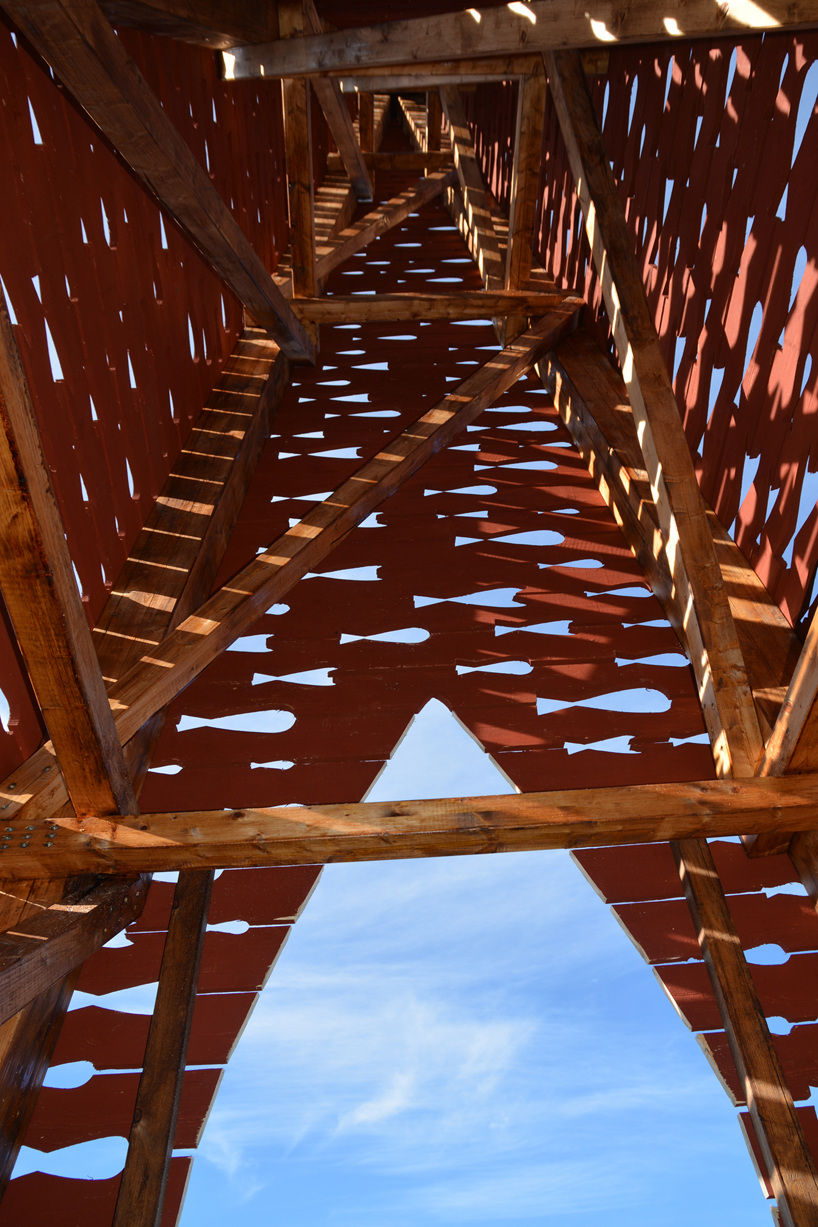 red timber pyramid beacon by ulf mejergren glows through fish cutouts on baltic sea island