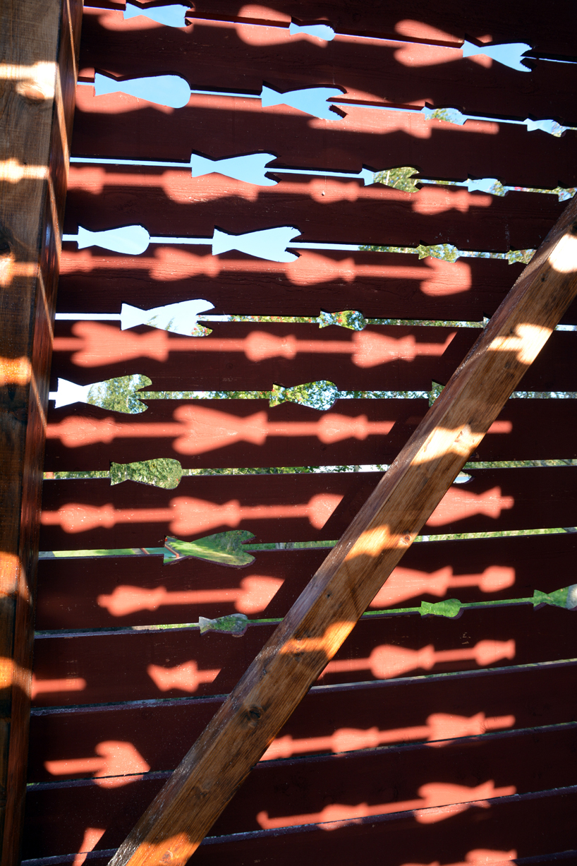 red timber pyramid beacon by ulf mejergren glows through fish cutouts on baltic sea island