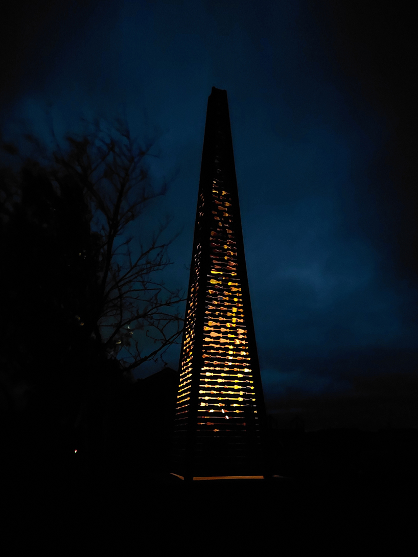 red timber pyramid beacon by ulf mejergren glows through fish cutouts on baltic sea island