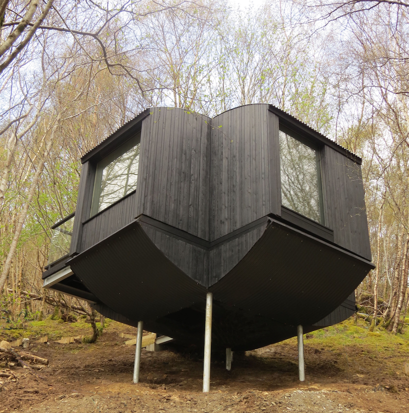 curved larch-clad tree house hovers above steep hillside in the scottish highlands