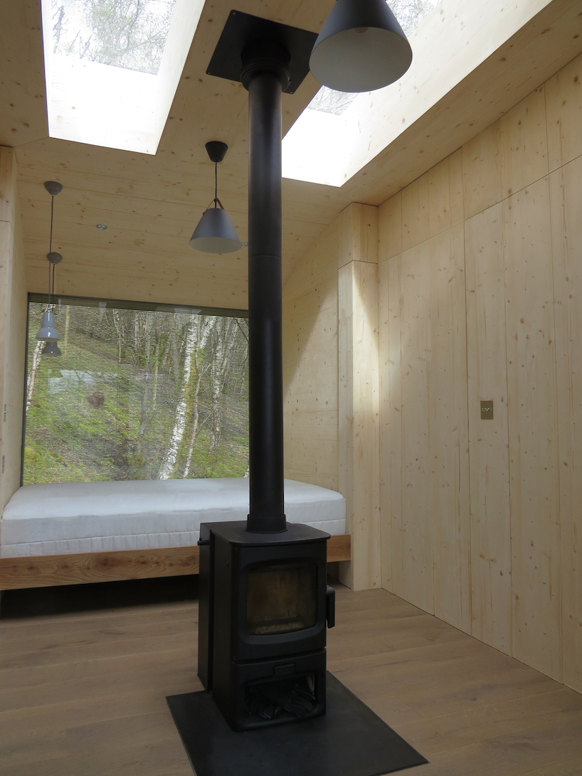 curved larch-clad tree house hovers above steep hillside in the scottish highlands