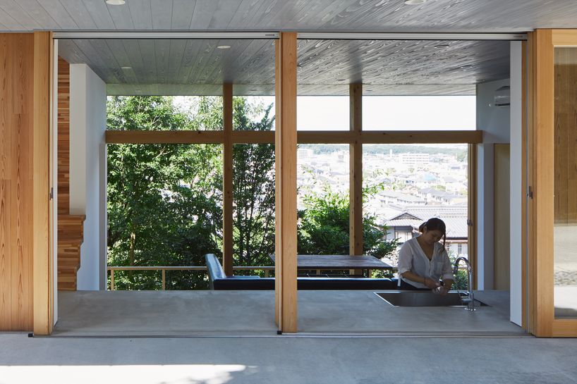 masaki ihara integrates house with tiered foundation into japanese hillside