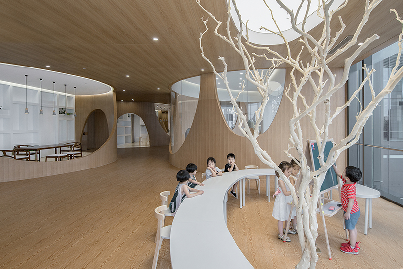 archstudio's children's art school features multiple ranges of artificial wood-clad hills