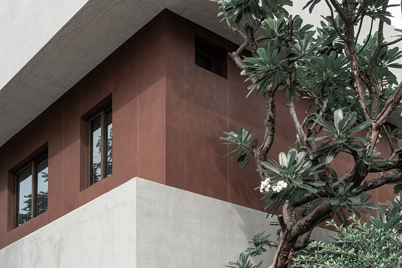 anonymous studio stacks geometric volumes of rust and mortar in Bangkok's tropical house