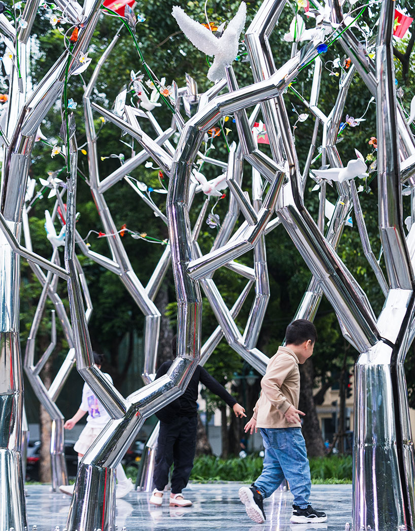 a circle of mirroring steel branches composes a luminous forest in hanoi's public realm