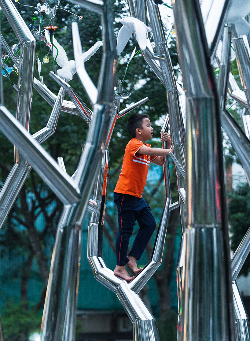 a circle of mirroring steel branches composes a luminous forest in hanoi's public realm