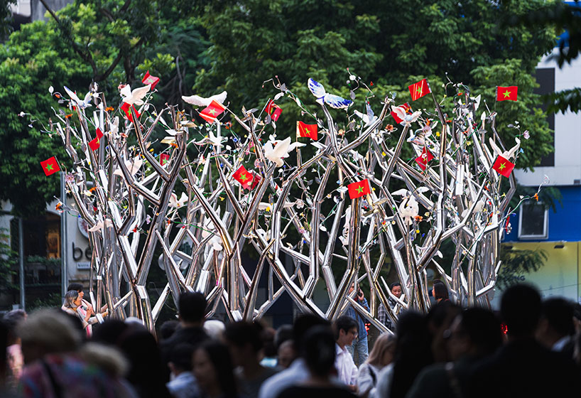 a circle of mirroring steel branches composes a luminous forest in hanoi's public realm