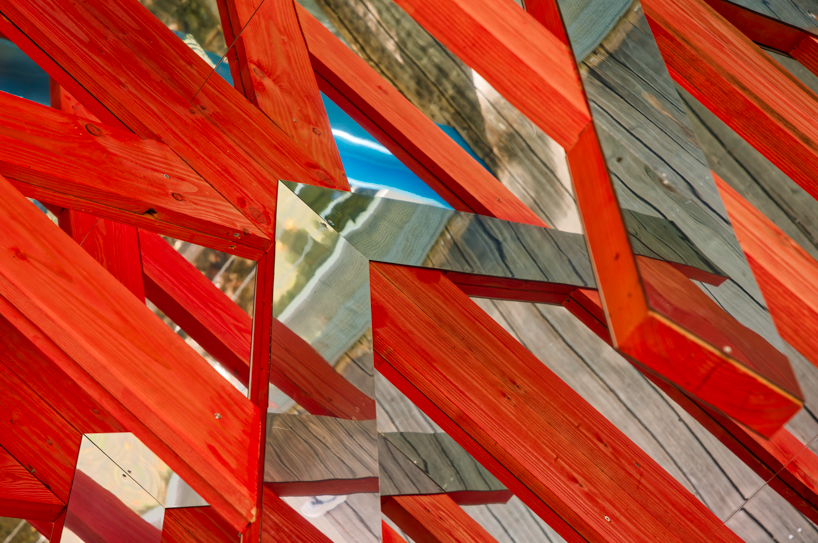 coral-toned timber and mirror canopy by GRRIZ transforms footbridge above river in france