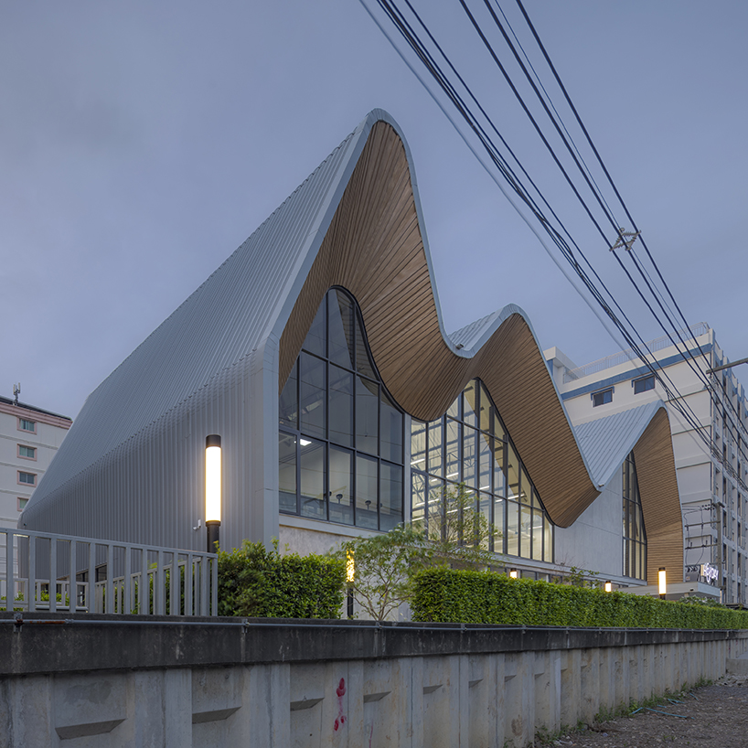 three asymmetrical curved gable roofs top ASWA’s community hub in thailand
