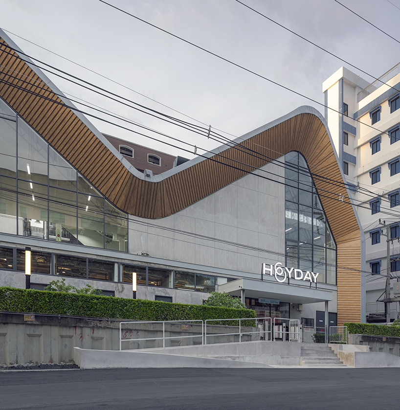 three asymmetrical curved gable roofs top ASWA’s community hub in thailand