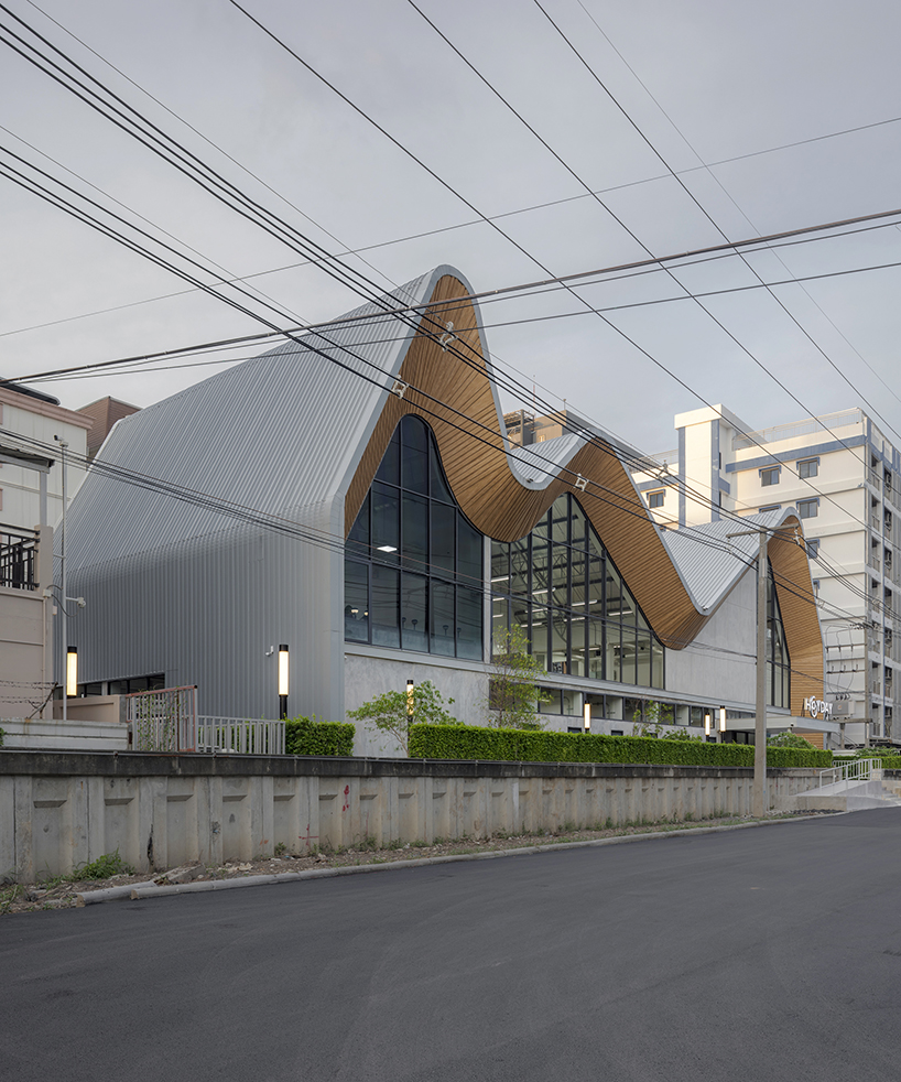 three asymmetrical curved gable roofs top ASWA’s community hub in thailand