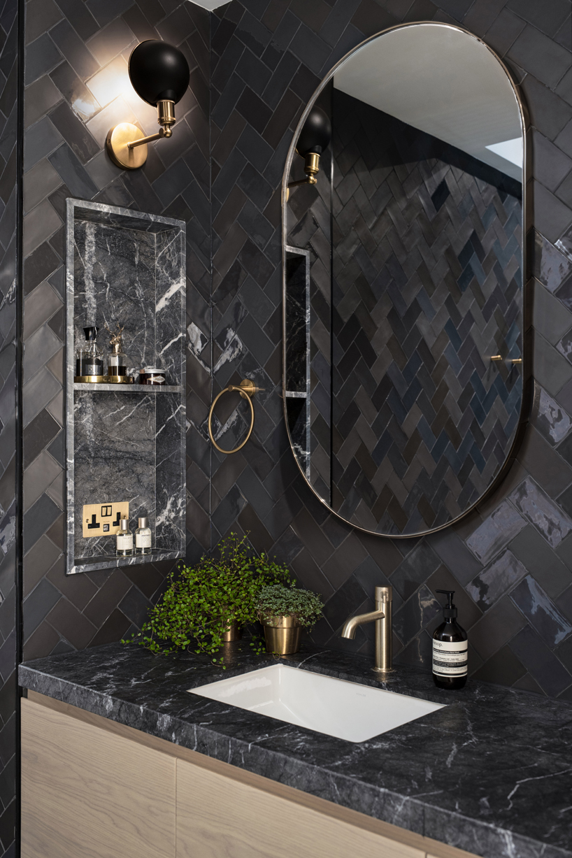 the master bathroom utilizes a moody colour palette and textures