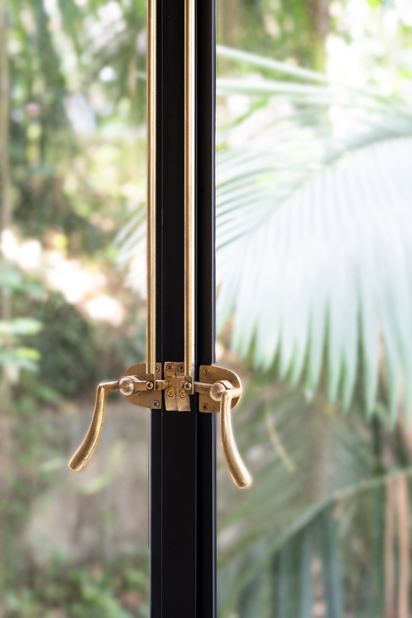 the black wooden blinds and delicate brass details accentuate the feeling of an elegant yet quaint summer home.