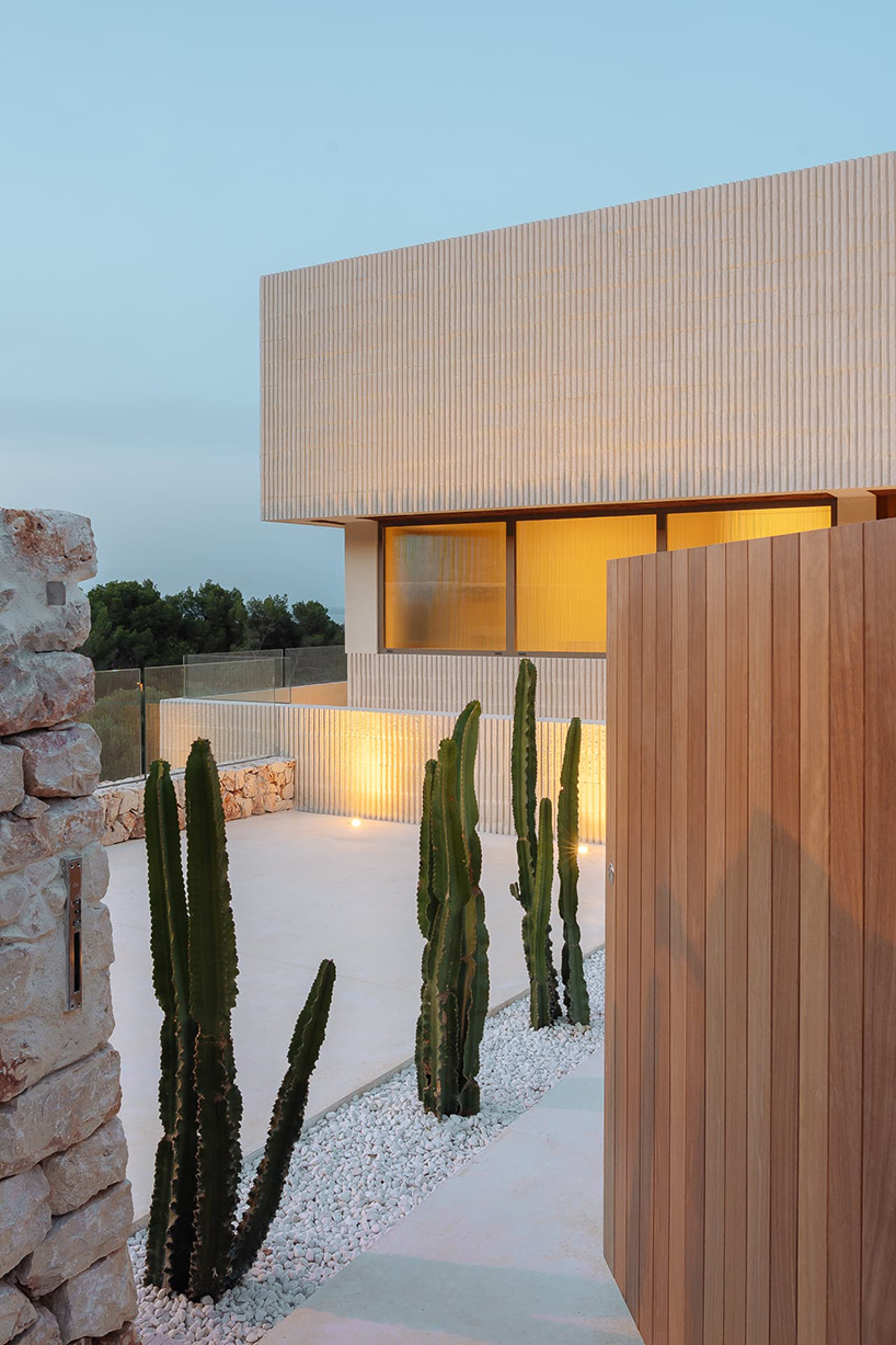 Muros de hormigón acanalados cortados por una serie de aberturas acristaladas enmarcan una casa de turno en España.
