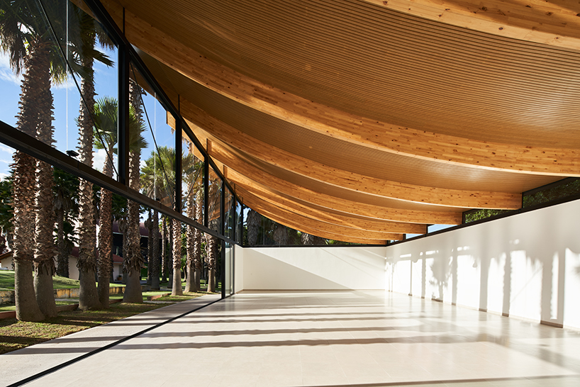 Vigas curvas de madera laminada forman un techo ligero en lo alto del Pabellón de La Coruña en Cambaia