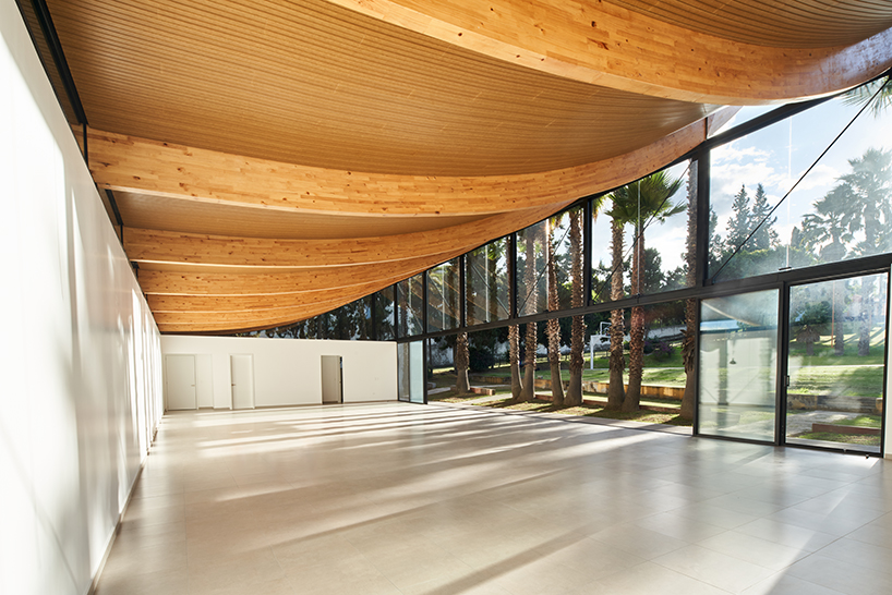 Vigas curvas de madera laminada forman un techo ligero en lo alto del Pabellón de La Coruña en Cambaia