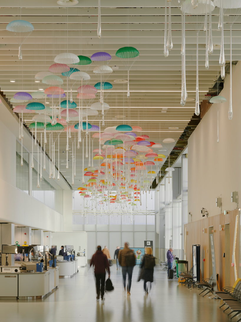 hundreds of suspended parachutes by lazerian drift above manchester airport’s terminal - 9