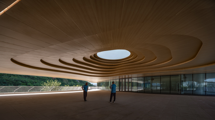 scale-like facade wraps hushan swimming center's undulating form by LYCS architecture