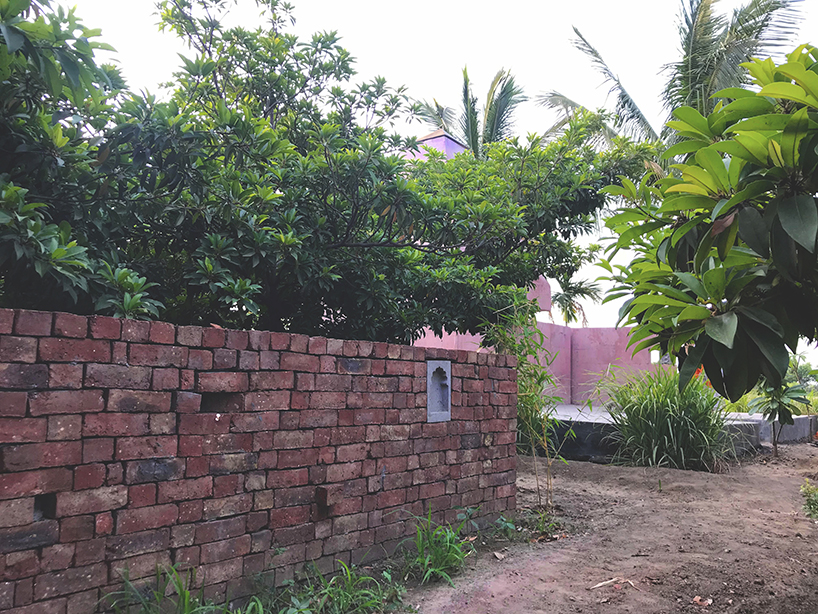 karan darda's orange hindu temple in india creates a contrast with green surroundings