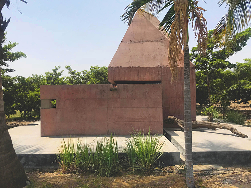 karan darda's orange hindu temple in india creates a contrast with green surroundings