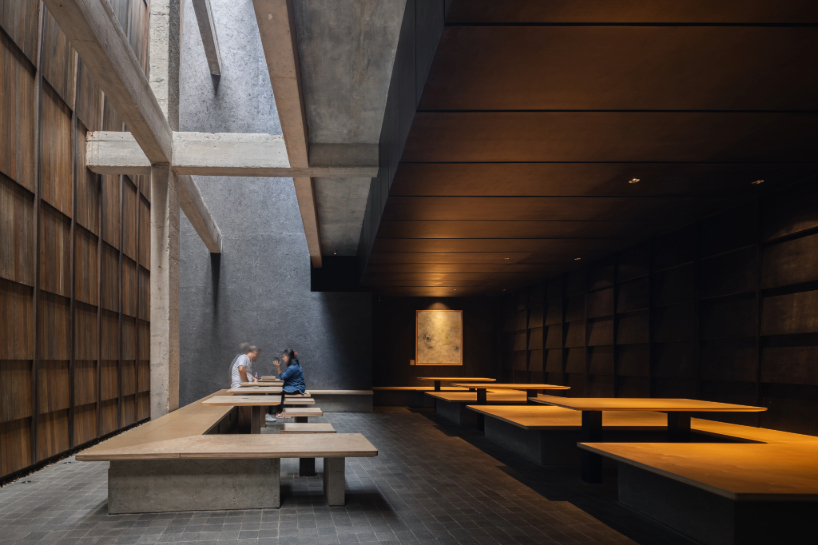 light and rain pour through internal courtyard within monochrome dessert shop in indonesia