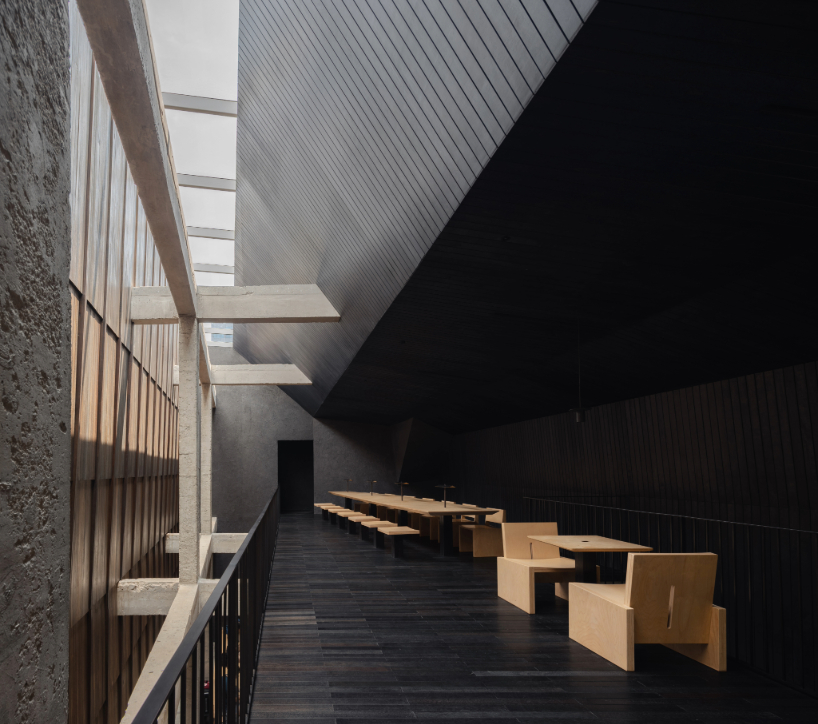 light and rain pour through internal courtyard within monochrome dessert shop in indonesia