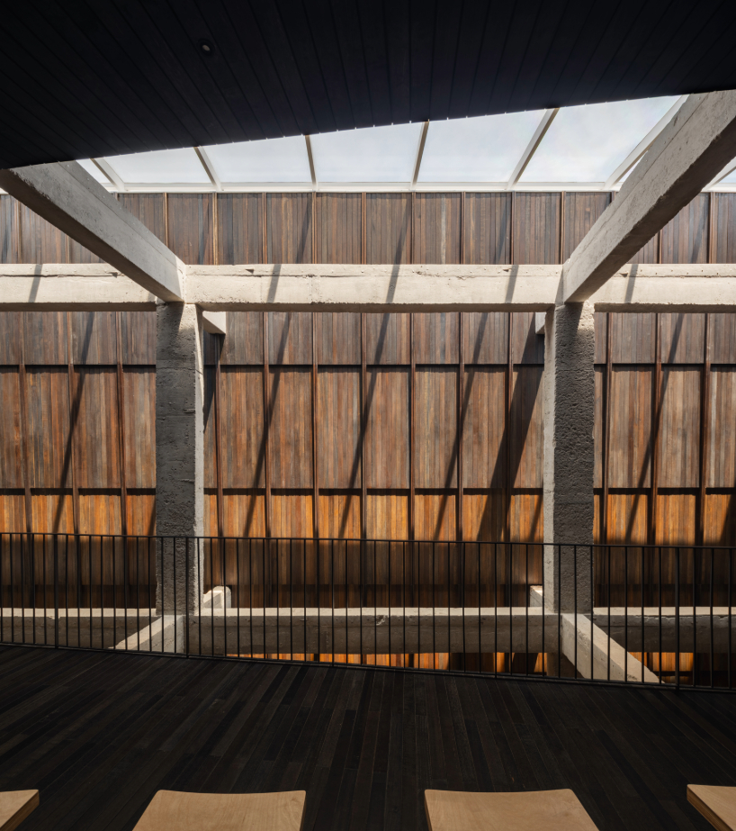 light and rain pour through internal courtyard within monochrome dessert shop in indonesia