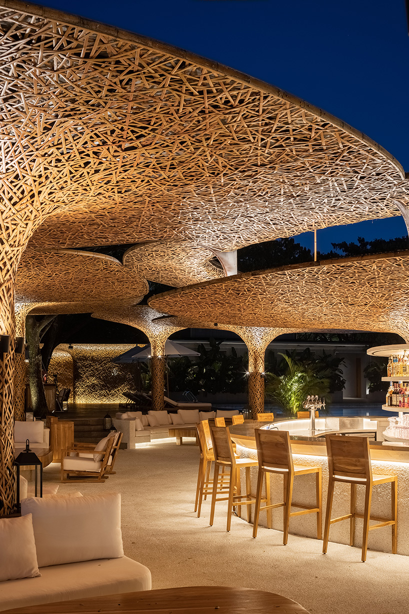 a cluster of bamboo canopies tops resort beach club by various associates amid china's coconut groves