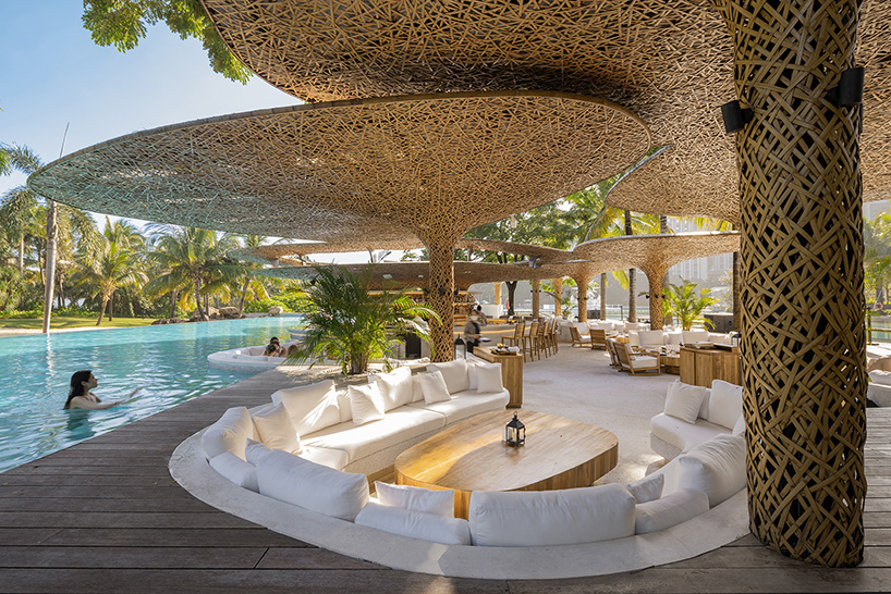 a cluster of bamboo canopies tops resort beach club by various associates amid china's coconut groves
