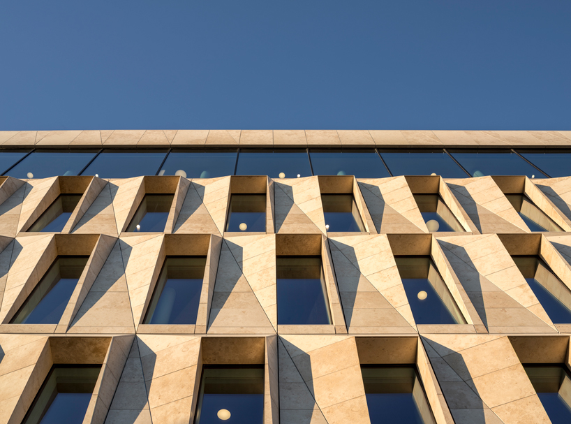 studio ALL's faceted stone facade plays with light on city hall in norway