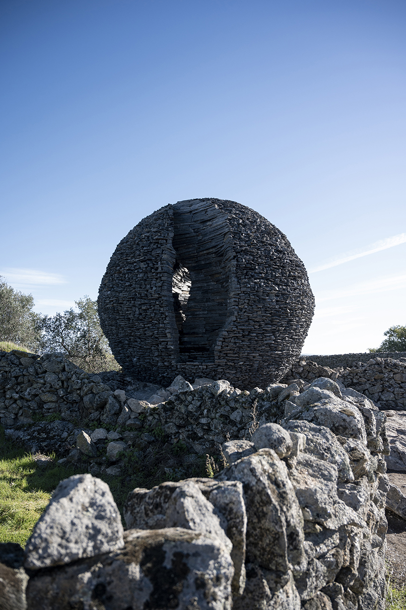 atelier yokyok sculpts sphere land installation out of black schist and granite in portugal