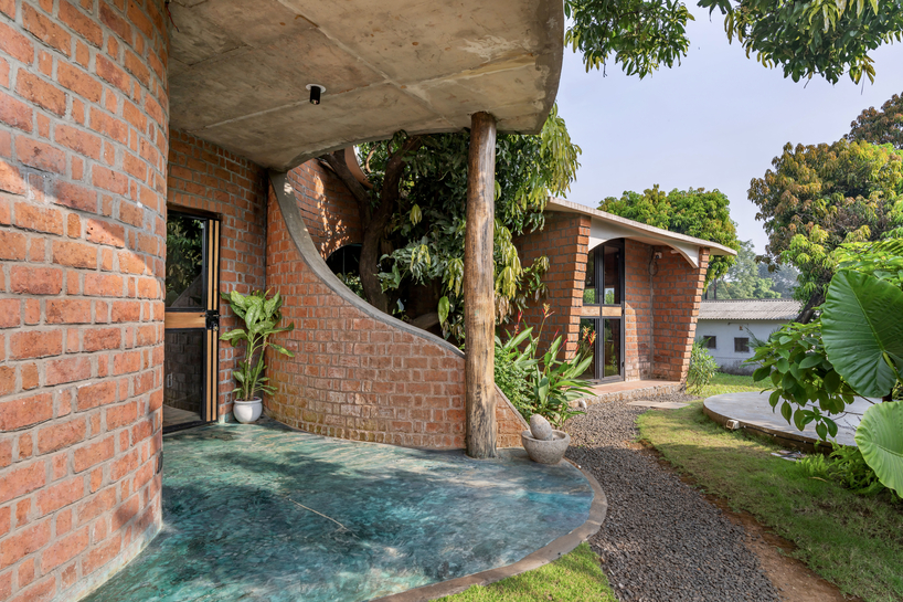 curved brick walls wrap biophilic farmhouse by blurring boundaries in mumbai mangro grove