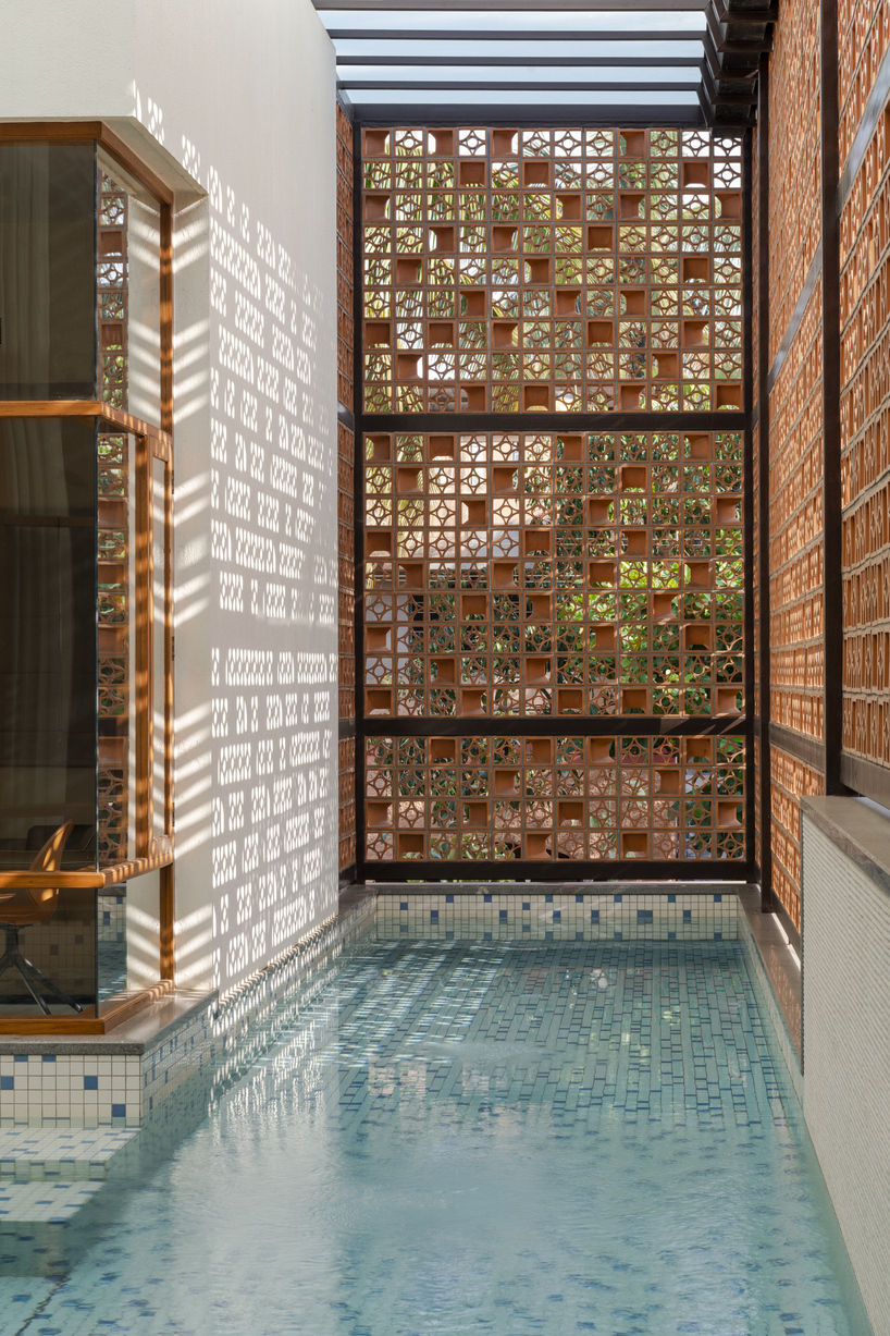 Pantallas de terracota perforadas encierran el pabellón de la piscina en una casa india