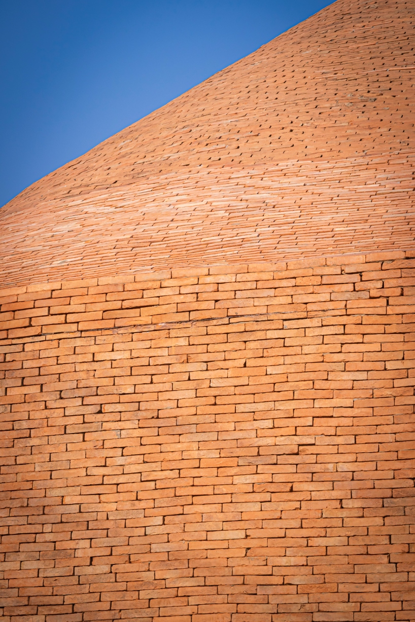 undulating brick facade wraps studio miti's athita pool villa and spa in thailand