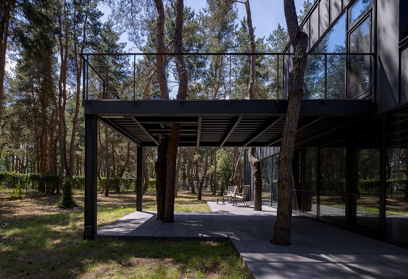 dark metal and wood cladding wraps gabled 'house among the pines' in ukraine
