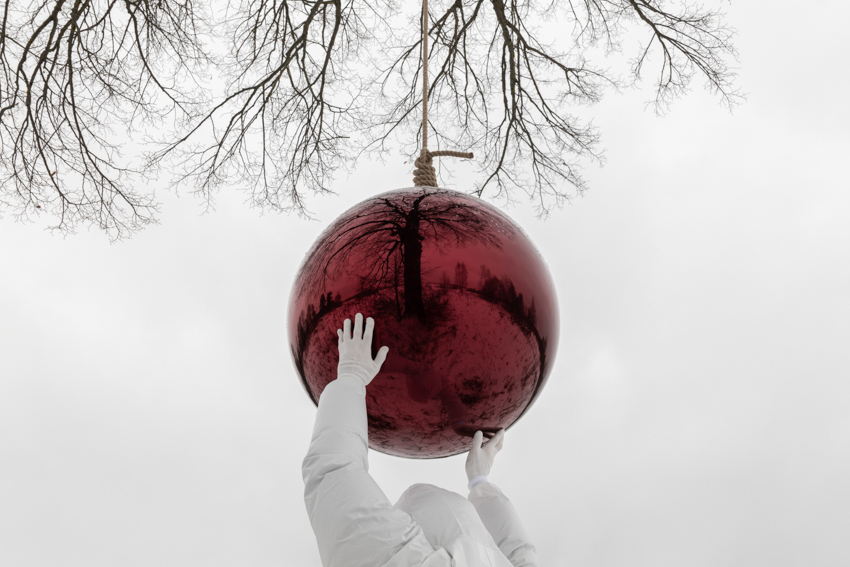 reflective red sphere suspends from tree in gregory orekhov&rsquo;s land art installation