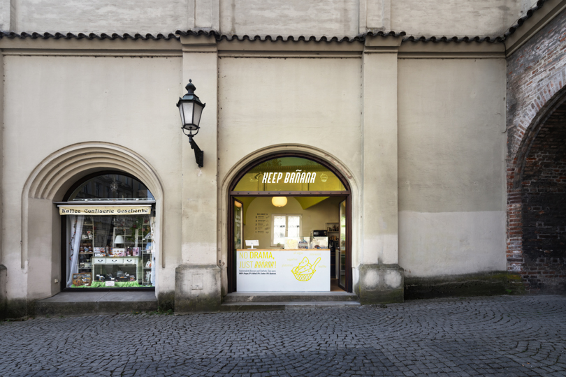 Yellow trapezoidal arch tops a german banana ice cream shop to create an optical illusion
