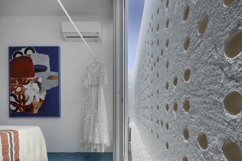 white perforated cubic facade wraps hybrid home and studio around a tree in brazil - 8